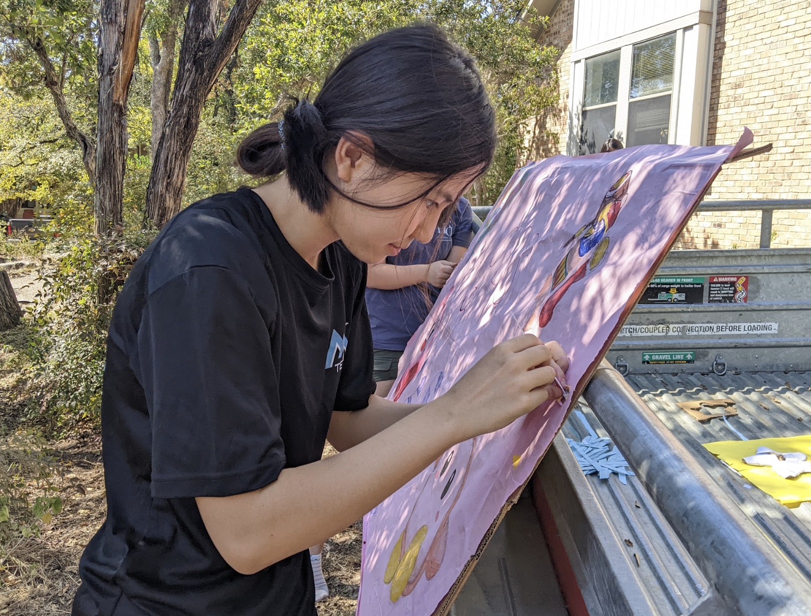 Staring intently, StuCo Freshman Class President Apple Ma zip-ties the Class of 2028 banner onto the Homecoming float. Volunteers spent more than three hours drawing Kirby and other Adventure of Sea characters on the poster. "This is our first year at high school," Reed Bassett '28 said. "When you think of high school, you think about Homecoming."